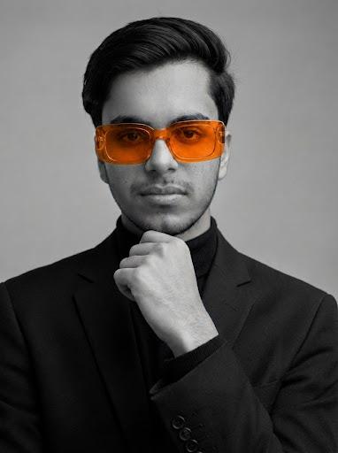 Muneeb Rehman wearing orange sunglasses and a black suit
